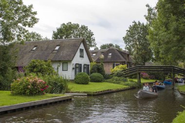 GIETHOORN, NETHERLANDS - 1 Ağustos 2017: Giethoorn 'daki bir kanalda tekne gezisinde bilinmeyen ziyaretçiler. Güzel evler ve bahçıvanlık şehri 