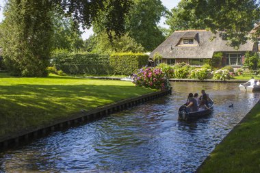 GIETHOORN, NETHERLANDS - 05 Ağustos 2015: Giethoorn 'daki bir kanalda tekne gezisinde bilinmeyen ziyaretçiler. Güzel evler ve bahçıvanlık şehri 