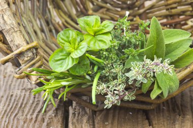 Ahşap arka plan üzerinde bir sepet içinde taze hasat otlar