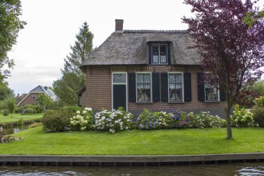 GIETHOORN, NETHERLANDS - evlerin ve bahçelerin tipik Hollanda ilçesi