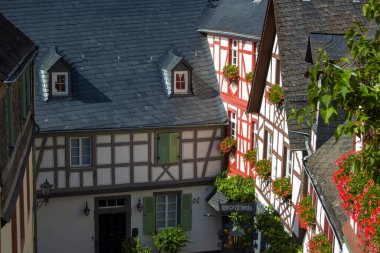 BEILSTEIN, GERMANY - SEPTEMBER 03 2022: Moselle nehri kıyısındaki tarihi köy eski ahşap evleri ve tepelerin tepesinde Metternich kalesinin kalıntıları var.