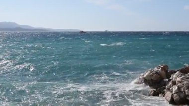 İyon Denizi 'nin güzel, nazik deniz dalgaları Arnavutluk' un Ksamil kentindeki çakıl taşı plajına çarpıp kayalara çarptı. Ilık ve aydınlık bir yaz gününde suyun ne kadar berrak ve renkli olduğunu gösteriyor..
