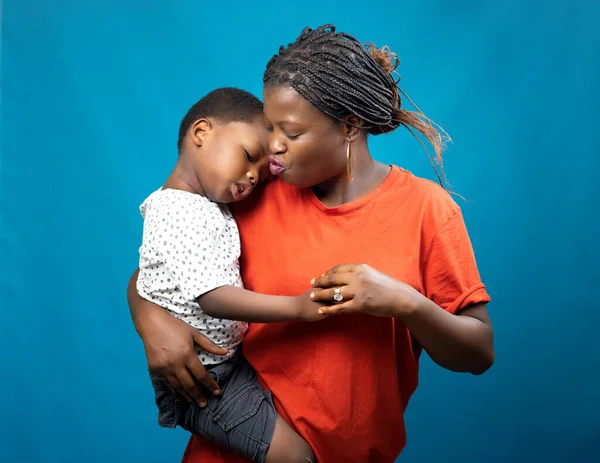 stock image A happy African mother, aunt or guardian caring for a little boy child as she carries him in her hands