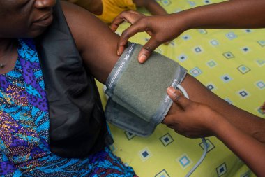 Gelişmiş teknolojik aygıtla tıbbi bir hastanın kan basıncını ölçen bir bakıcı.