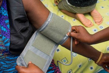 Gelişmiş teknolojik aygıtla tıbbi bir hastanın kan basıncını ölçen bir bakıcı.