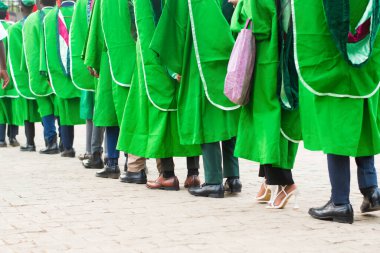 Line up of university graduating students wearing their green graduation outfit and marching towards the school reception hall for their pass out ceremony in Nigeria