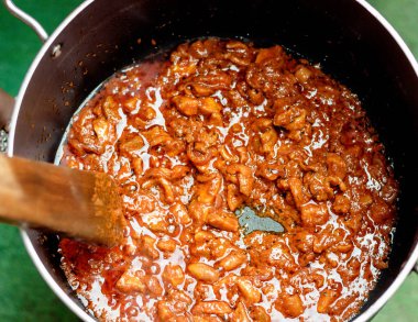 Close up shot of a cooking pot containing stew sauce and a wooden spatula, in preparation to cooking a healthy, nutritional and delicious meal