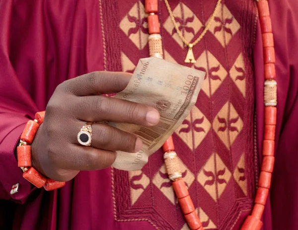 stock image A yoruba groom from Nigeria holding one thousand Naira Nigerian cash or money in his hand during a traditional wedding engagement ceremony