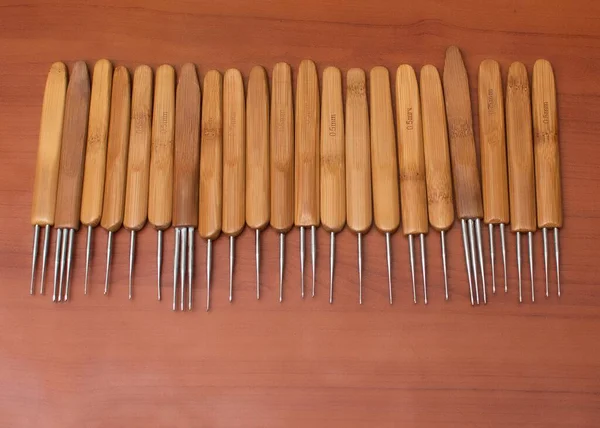 Multiple wooden hair crochet tools placed on a plywood table, arranged on a straight line for sales inside a saloon and fashion business shop in Nigeria