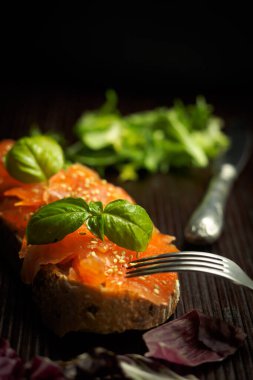 Baharatlı somon, fesleğen ve susamlı ekmek dilimi.