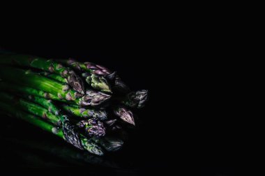 Siyah arka planda bir sürü taze kuşkonmaz, gurme konsepti.