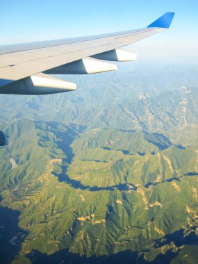 Dağların üzerinde uçan bir uçağın kanadı. Seyahat konsepti. Fotoğraf turizm operatörlerine uygulandı.