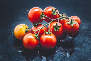 Koyu metal arkaplanda kiraz domatesleri.