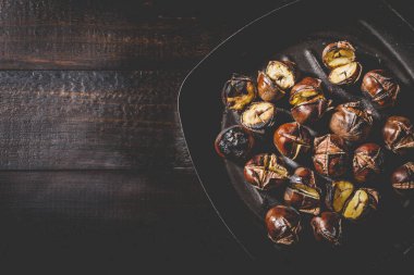 Demir ızgarada kavrulmuş kestaneler ahşap tahta üzerinde, üst manzara, kopyalama alanı.