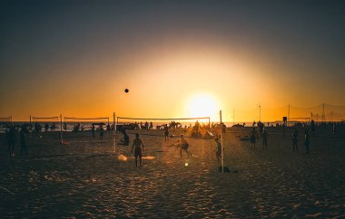 Cadiz, İspanya - 3 Ağustos 2023: La Victoria Plajı, genç insanlar sıcak günbatımı ışığında kumsalda voleybol oynuyorlar. Playa Victoria, Cadiz 'in batı yakasında, Costa de la Luz' da yer alan bir şehir plajı..