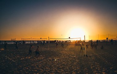 Cadiz, İspanya - 3 Ağustos 2023: La Victoria Plajı, genç insanlar sıcak günbatımı ışığında kumsalda voleybol oynuyorlar. Playa Victoria, Cadiz 'in batı yakasında, Costa de la Luz' da yer alan bir şehir plajı..