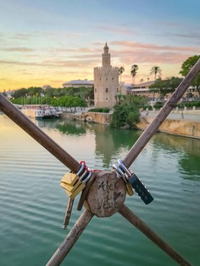 Altın Kule (Torre del Oro) ve gün batımında Guadalquivir nehri ile Seville Köprüsü 'nde asma kilit.