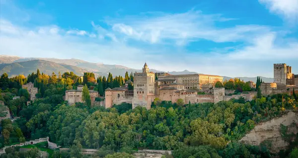 Alhambra Sarayı, Granada, İspanya. Bahçeleri ve etrafındaki duvarları ile Alhambra Sarayı öğleden sonra güneşinde parlıyordu. Arkasında Sierra Nevada dağları vardı.