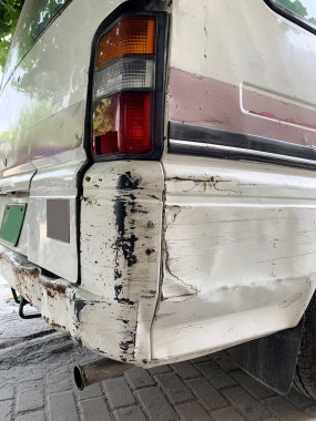 Beyaz bir arabanın arkasında kırık sinyal lambası var. Seçici odak, yolda beyaz minibüsün arkası zarar görmüş. Yıpranmış Vintage Kamp Minibüsünün Fren Işığı Detayları. 