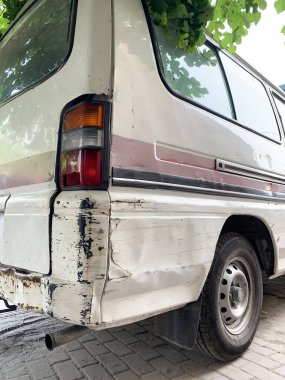 Beyaz bir arabanın arkasında kırık sinyal lambası var. Seçici odak, yolda beyaz minibüsün arkası zarar görmüş. Yıpranmış Vintage Kamp Minibüsünün Fren Işığı Detayları. 