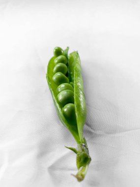 Yeşil taze bezelye sebzeleri beyaz pamuk kumaşa konur..