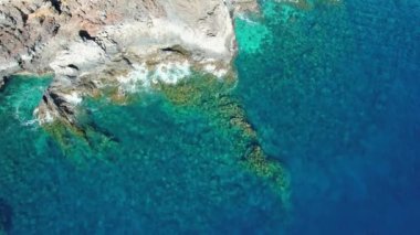 Top view of the clear blue ocean near the rocky coast of El Hierro, Canary Islands. Static aerial drone footage. Beautiful natural seascape and shore.