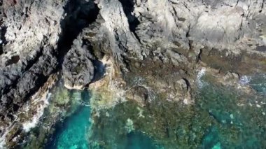 Blue Atlantic Ocean gently waving against volcanic rocks. Aerial top down static view. El Hierro, Canary Islands.