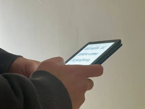 Elinde kitap okuyucusu olan çocuk.