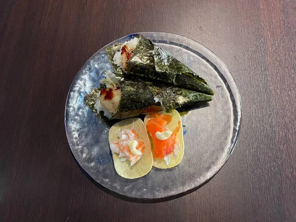 Plate with salmon and shrimp tacos and temaki sushi with shrimp tempura