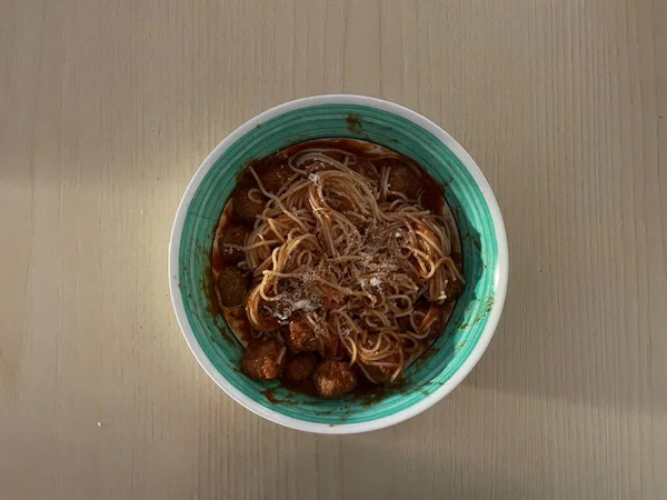 Ahşap masada domates soslu ilk spagetti yemeği.