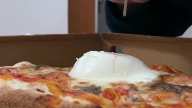 Çatal ve bıçakla pizza üzerine burrata mozzarella peyniri kes.