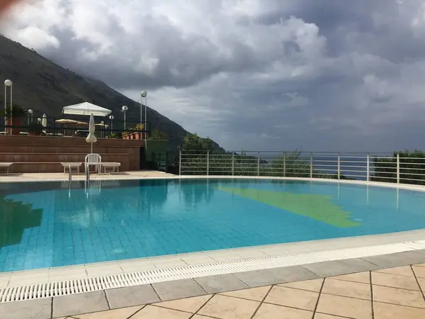 Dağlar ve deniz arasındaki açık havuzda tatil.