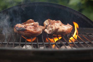 Tavuk göğsü barbeküde alevler içinde yatıyor.