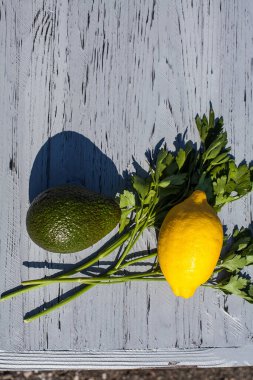 Aperatif avokado, taze limon ve otlardan oluşan bir mutfak kompozisyonu, mutfaktaki açık ahşap bir masada maydanoz..