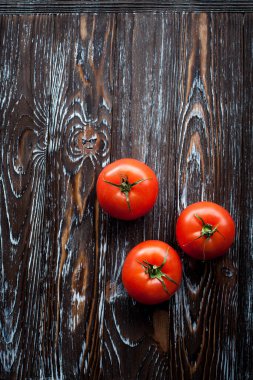 Ahşap desenli bir masa üzerinde olgun kırmızı büyük domateslerin mutfağında iştah açıcı bir kompozisyon..
