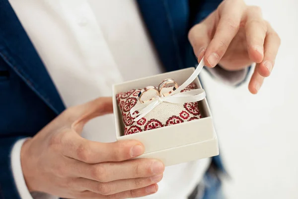 Groom Holds Gold Wedding Rings Decorative Box Small Pillow Ribbons — Stockfoto