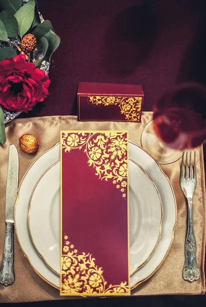 桌子上的构图由餐具 白盘和红金相间的节日卡片组成 桌子上装饰着花和金黄的核桃 — 图库照片