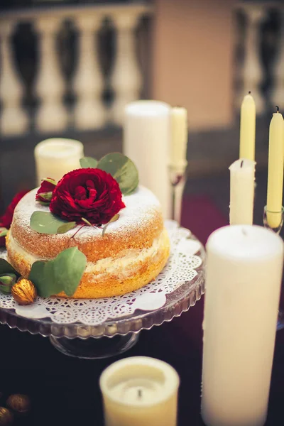 在餐馆里 桌上摆放着一个装饰着蜡烛和金核桃的喜庆蛋糕 上面放着一朵红玫瑰 — 图库照片