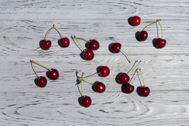Olgun kırmızı kirazlar gün boyunca açık dokulu ahşap bir masada yatar..