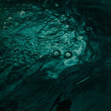 A dark green fabric with folds lies underwater with waves and splashes. Image for your creative design or stylish illustrations.