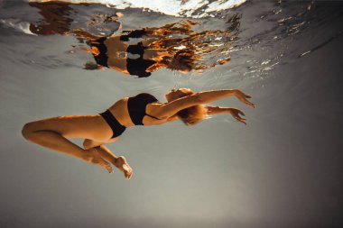 Sanat eserleri. Zayıf, bronz tenli, atletik vücutlu, sarı saçlı, siyah iç çamaşırlı bir kız havuza dalıyor. Tasarım ve dekorasyonunuz için estetik resim.