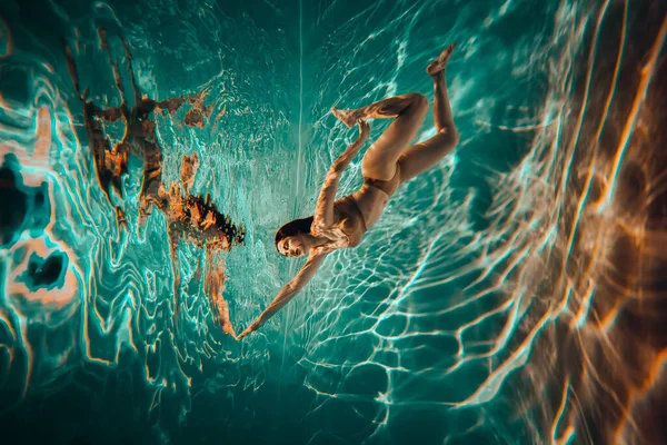 艺术品 一名身穿米色内衣的游泳女运动员在游泳池里拍的水下照片 照片上有漂亮的亮点 — 图库照片