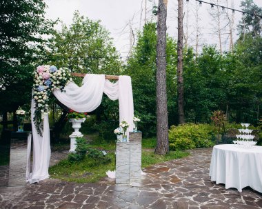 Kumaş ve doğal çiçeklerle süslü bir düğün kemeri. Şampanya kadehleri piramidi olan bir masa. Tasarımınız veya çizimleriniz için yaratıcı resim.