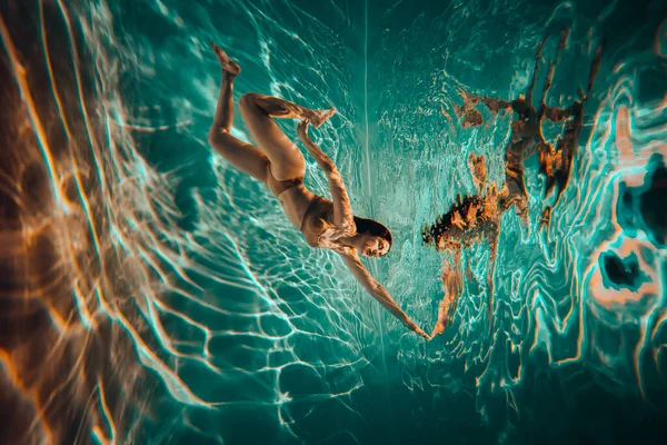 艺术品 一名身穿米色内衣的游泳女运动员在游泳池里拍的水下照片 照片上有漂亮的亮点 — 图库照片