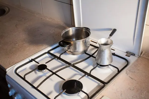 台所の白いガスコンロには金属製の鍋とケトルが立っています あなたの創造的な装飾やデザインの画像 — ストック写真