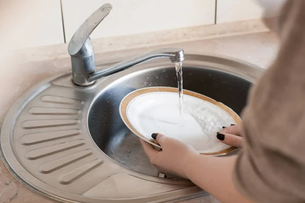 少女は台所で皿を洗う プロットは家事 清潔さと毎日の活動についてです 軽い家具 質感のカウンター 水道水がタップから流れます — ストック写真