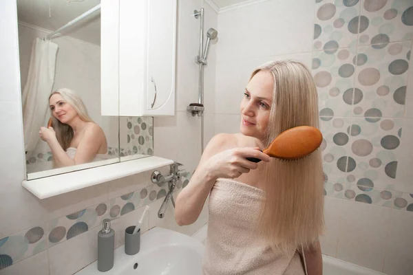 Μια Ξανθιά Γυναίκα Λευκή Πετσέτα Χτενίζει Μακριά Ξανθά Μαλλιά Της — Φωτογραφία Αρχείου