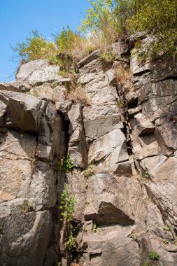 Resimli dokular, büyük taşlardan yüksek uçurumları dizaynınız ya da çizimleriniz için bir arka plan olarak şekillendirdi. Ağaçlar ve yeşil çalılar uçurumun zirvesinde yetişir. Tasarım ve yaratıcı çizimleriniz için bir arkaplan olarak bir resim.