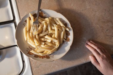 Tabakta sıcak makarna ve mutfakta çatallı bir el. Yaratıcı dekorasyon ve tasarım için resim.