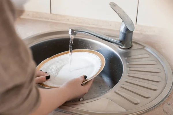 少女は台所で皿を洗う プロットは家事 清潔さと毎日の活動についてです 軽い家具 質感のカウンター 水道水がタップから流れます — ストック写真
